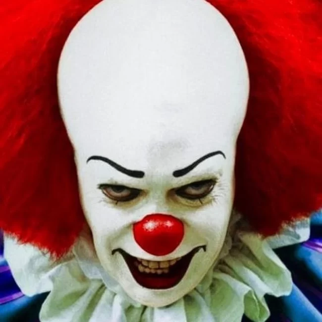 Close-up of Pennywise the Clown with an evil grin and red hair.